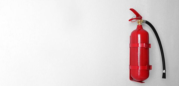 Fire extinguisher hanging on white wall, space for text. Banner design - Foto, Imagem
