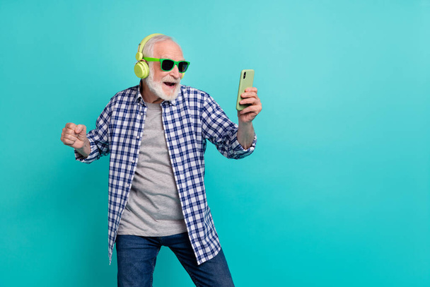Photo of confident hipster pensioner man have fun listening favorite music chatting with friends isolated on turquoise color background. - Foto, Imagen
