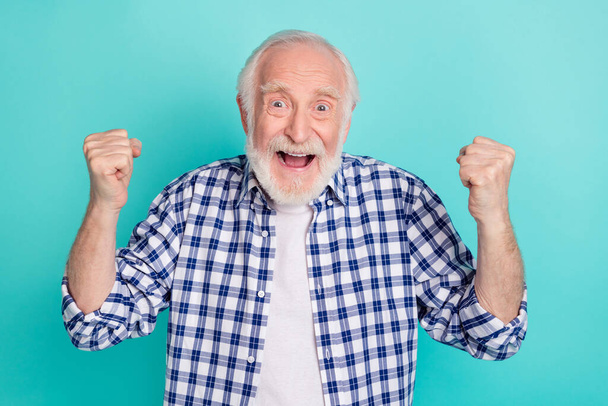 Photo of cheerful overjoyed ecstatic granddad raise fists in victory triumph win lottery isolated on teal color background. - Foto, Imagem