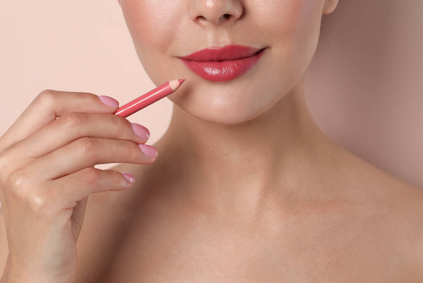 Young woman with beautiful pink lip pencil on light background, closeup - Fotografie, Obrázek