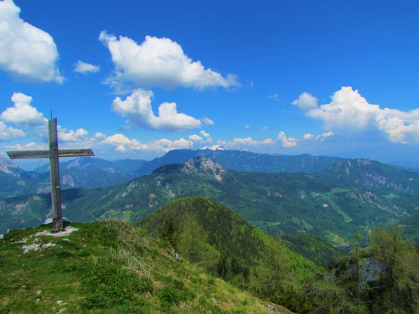 Vista de la colina sobre Jezersko en la región de Gorenjska de Eslovenia con el pico cubierto de nieve de Pristovski Storzic en la parte posterior tomada de Goli Vrh con una cruz de madera en el lado - Foto, imagen