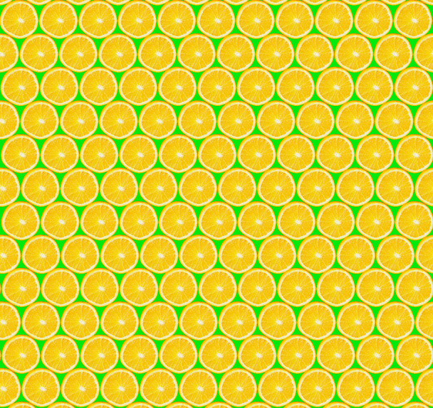 Textuur van gesneden sinaasappelschijfjes op groene achtergrond. Snijd stukjes sinaasappel. Een gezonde levensstijl. Gezonde voeding. Verse vruchten - Foto, afbeelding