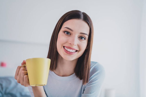 Photo of adorable sweet young lady dressed blue shirt smiling enjoying tasty morning beverage indoors house room. - Фото, изображение