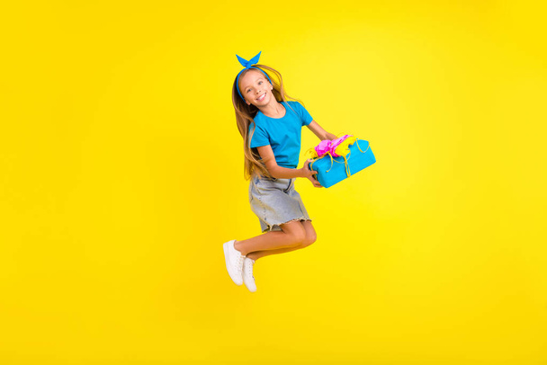 Full length portrait of excited overjoyed girl jump hands hold giftbox isolated on yellow color background. - Foto, afbeelding