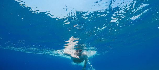 Το αγόρι κολυμπάει ελεύθερα στον ανοιχτό ωκεανό. Υποβρύχια - Φωτογραφία, εικόνα
