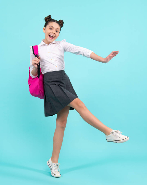 Back to school. Teenager schoolgirl in school uniform with backpack. School children on isolated studio background. Happy teenager, positive and smiling emotions of teen girl - Fotó, kép