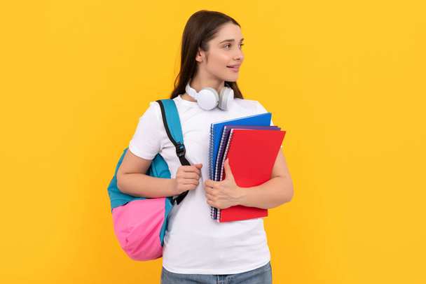 正の学生はノートを持ってる。黄色い背景にノートを持ってる女の子。コピーとヘッドフォン付きの私立教師です。学校に戻って。現代教育の概念は. - 写真・画像