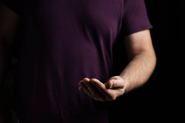 Empty male hand, palm up on a black background. Giving, asking concept. - Foto, afbeelding