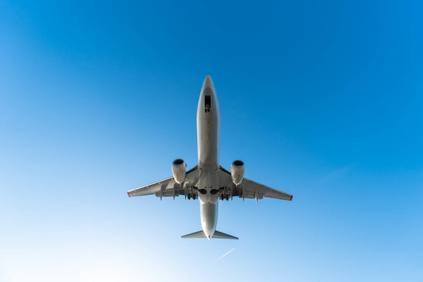 Close-up view from below of a departing plane with landing gear on a blue sky background on a sunny day, copy space - Foto, Imagen