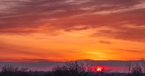 The sun rises from the horizon against the background of colorful clouds in the sky time lapse - Filmati, video
