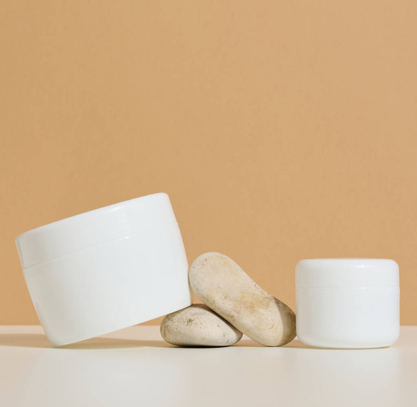 vaso di plastica rotondo bianco per prodotti cosmetici su sfondo marrone. Blank per prodotti di branding, mock up - Foto, immagini