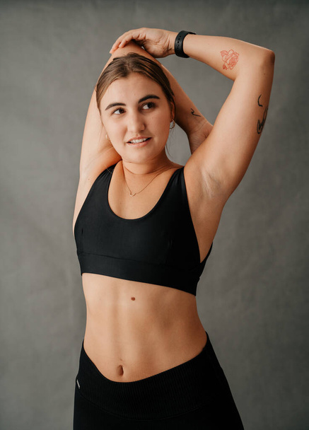 Young Caucasian Woman toned body doing arm stretching exercises in the studio . High quality photo - Photo, image