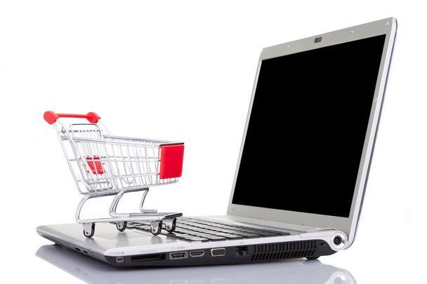 Winkelwagentje over een laptopcomputer, geïsoleerd op witte CHTERGRO - Foto, afbeelding