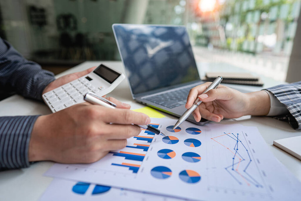 Dwóch partnerów biznesowych omawia wykresy planowania finansowego i firmowego podczas spotkań budżetowych, a biznesmen planuje analizę marketingu inwestycyjnego na laptopie w biurze. - Zdjęcie, obraz