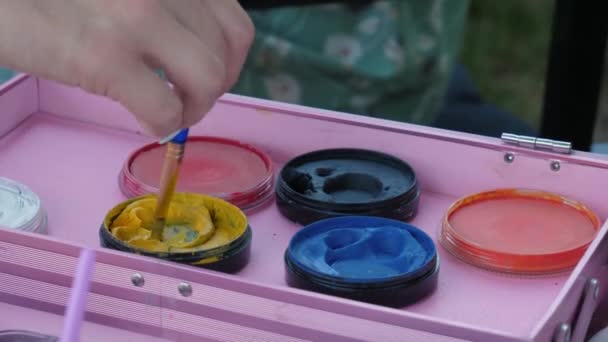 Die weibliche Hand des Künstlers taucht den Pinsel in die gelbe Farbe zum Malen auf den Körper, Nahaufnahme - Filmmaterial, Video