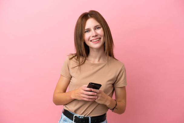 Young English woman isolated on pink background sending a message with the mobile - Фото, изображение