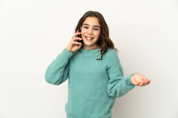 Pequeña chica caucásica aislada sobre fondo blanco manteniendo una conversación con el teléfono móvil con alguien - Foto, Imagen