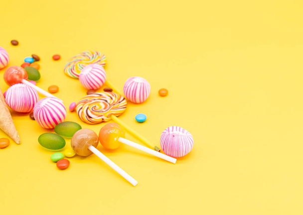Colorful different kinds of candies isolated on yellow background - Foto, immagini
