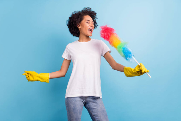 Photo of young excited crazy cheerful dreamy afro girl cleaning singing karaoke isolated on blue color background. - Fotografie, Obrázek