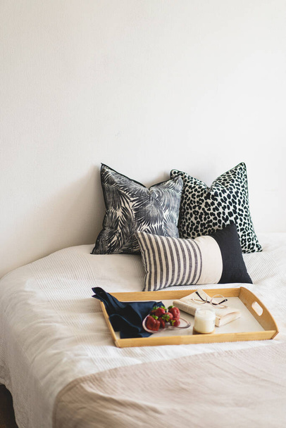 Linen pillows on a white bed with home decor. Still life details in home on a bed. Cozy home. Sweet home - 写真・画像