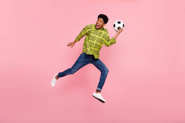 Full body photo of amazed brunette man jump wear jeans hold football isolated on pink color background. - Foto, Imagem