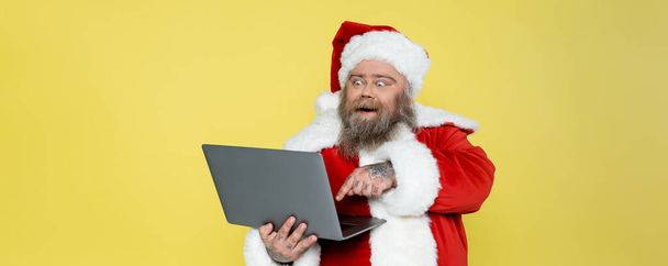 excited plus size man in christmas costume pointing at computer isolated on yellow, banner - Fotoğraf, Görsel
