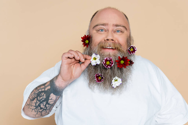 happy and chubby man showing beard with floral decor isolated on beige - Foto, Imagen