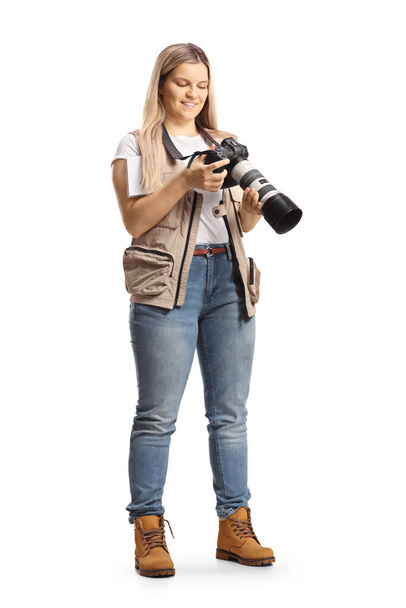 Fotografía completa de una reportera femenina sosteniendo una cámara aislada sobre fondo blanco - Foto, Imagen