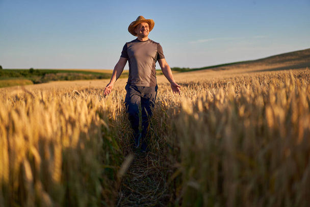 Happy farmer in a ripe wheat field at sunset - Foto, imagen