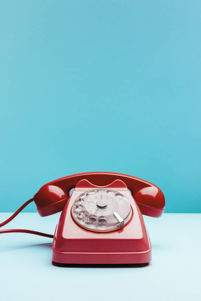 Old red telephone on blue background - Fotoğraf, Görsel