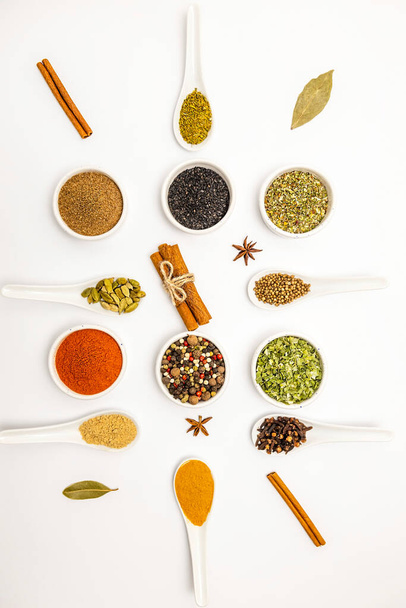 Top view, set of different culinary spices in white ceramic bowls and spoons, on white background - 写真・画像