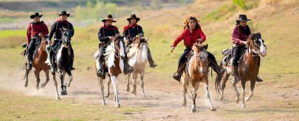 Skupina kovbojů a cowgirl jízda na koni na silnici s vysokou rychlostí v blízkosti vodní nádrže s denním světlem. - Fotografie, Obrázek