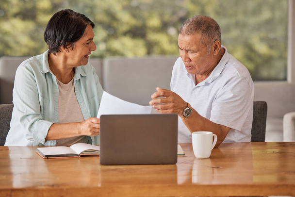 Elderly couple paying bills online on a laptop, sitting by a table at home getting angry, planning retirement. Senior hispanic man and woman having a dispute over finance and debt. - Photo, Image