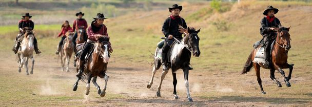 Gruppo di cowboy e cowgirl cavalcare cavallo su strada ad alta velocità vicino serbatoio d'acqua con luce diurna. - Foto, immagini