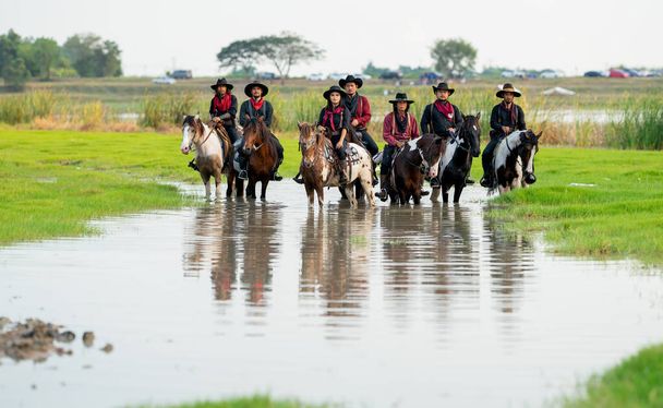 Gruppo di cowboy e cowgirl con cavalletto in serbatoio d'acqua con luce diurna. - Foto, immagini