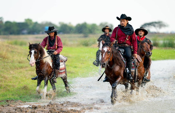 Grupo de cowboy e cowgirl cavalo de passeio através da água em reservatório com luz do dia. - Foto, Imagem