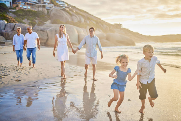 Wielopokoleniowa rodzina trzymająca się za ręce i spacerująca razem po plaży. Biała rodzina z dwójką dzieci, dwójką rodziców i dziadkami cieszącymi się wakacjami. - Zdjęcie, obraz