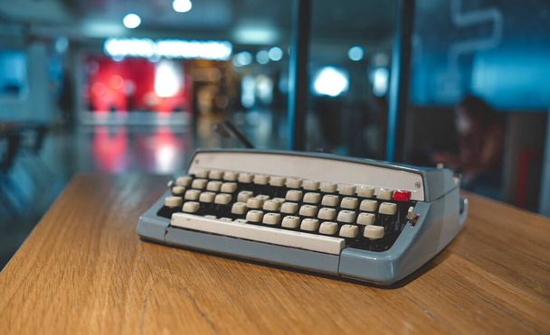 Máquina de escribir antigua retro sobre fondo borroso y frente a mesa de madera. Concepto Vintage - Foto, Imagen