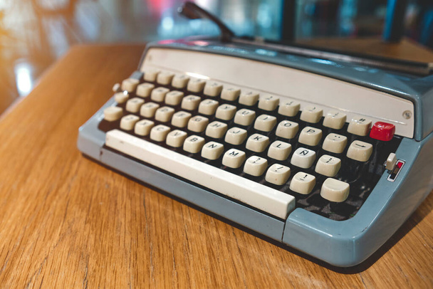 Retro old typewriter on blur background and front of wooden table. Vintage concept - Photo, image
