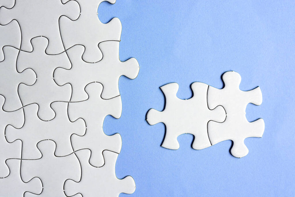 White puzzles and purple background. Concept of idea, discovery, difference, unique. Business concept. Copy space. Flat lay. - Photo, Image