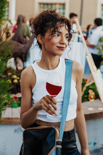 woman smiling seductively, drinking cocktail outdoors on sunset - Photo, Image