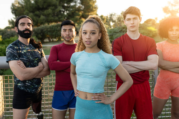 group of multiracial friends wearing sportswear outside, focus on curly blonde haired Hispanic woman - Foto, afbeelding