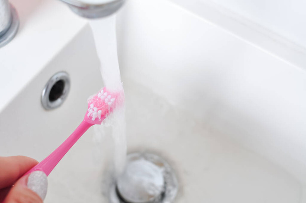Günlük temizlik için pembe diş fırçası, sabah rutini, banyo aksesuarları. - Fotoğraf, Görsel