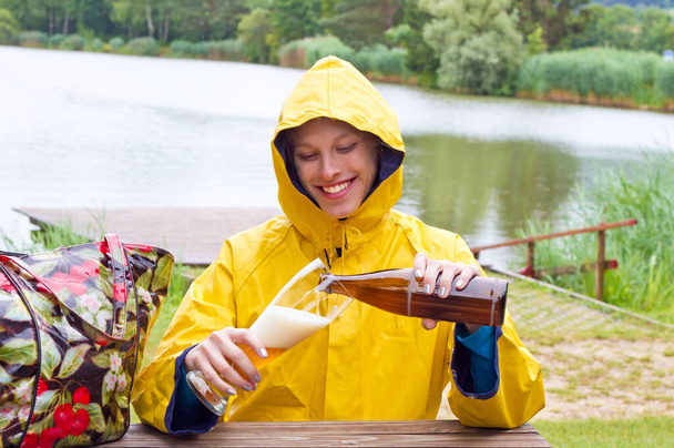Giovane donna felice che beve una birra di grano sotto la pioggia - Foto, immagini