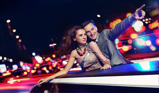 Elegant couple traveling a limousine at night - Фото, изображение