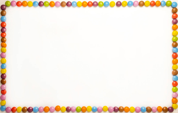 Rectangular horizontal photo frame on a white background with chocolates of different colors on the edge, photophone, birthday card - Foto, afbeelding