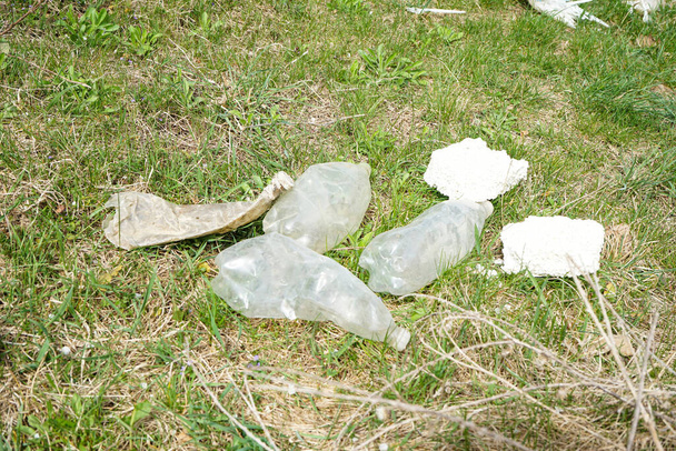 A pile of rubbish in a clearing in the countryside on a spring day. Plastic bottles, concept of ecology. - Zdjęcie, obraz
