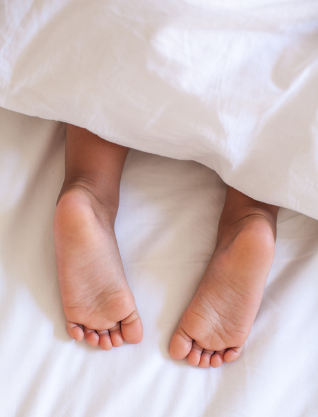 Child feet under the blanket. - Zdjęcie, obraz