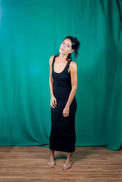 Портрет дорослої моделі в чорній сукні на темно-зеленому фоні. Сальвадор (Баїя, Бразилія).. - Фото, зображення