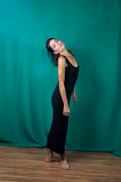 Портрет взрослой модели в черном платье на темно-зеленом фоне. Сальвадор, Бахия, Бразилия. - Фото, изображение